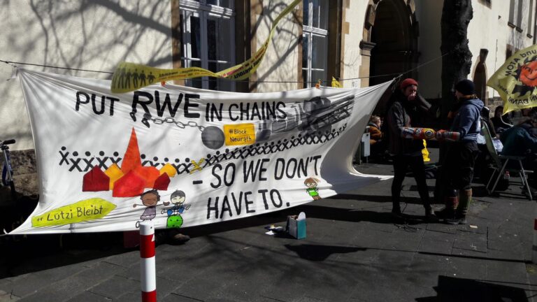 People in solidarity stand in front of the court holding a banner.